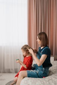 Parent carefully checking a child's hair section by section with a fine-tooth metal lice comb in soft daylight.