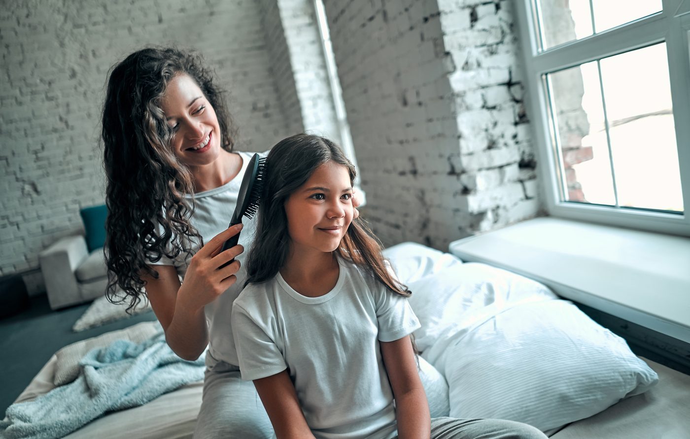 Mother brushing daughter's hair calmly at home, representing families served by Lice Lifters of Greater Washington