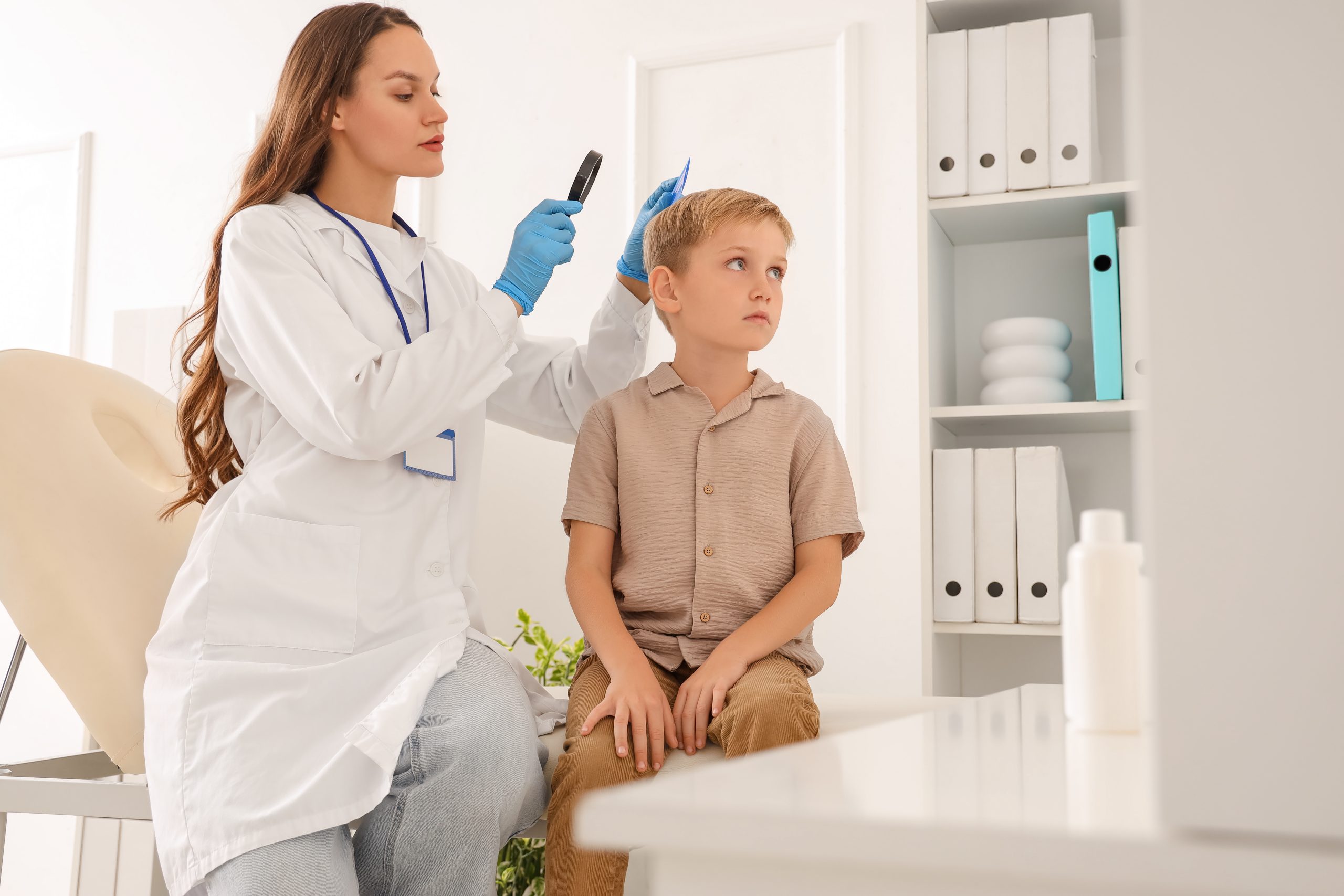 Doctor using a magnifier to check a child's hair for head lice during a clinic visit