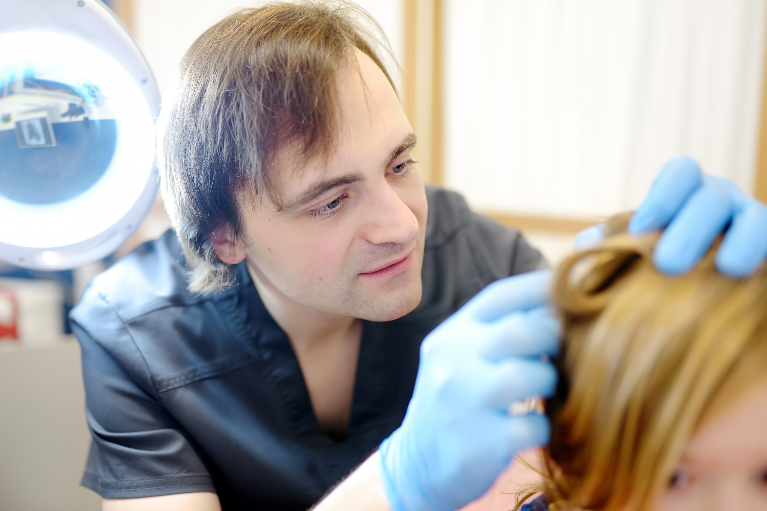 A lice technician checks a young child's scalp and hair during a professional lice screening in a Silver Spring clinic