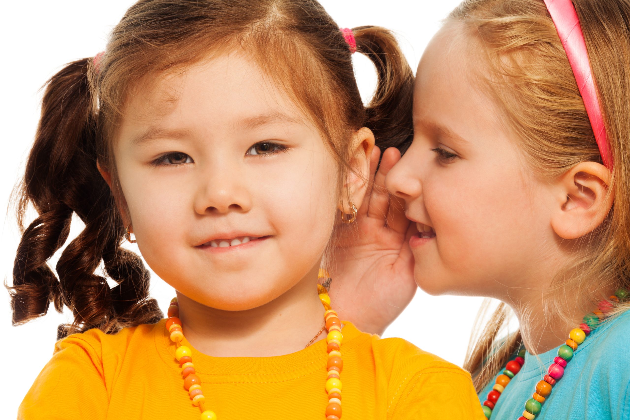 Children whispering close together to show head-to-head lice transmission