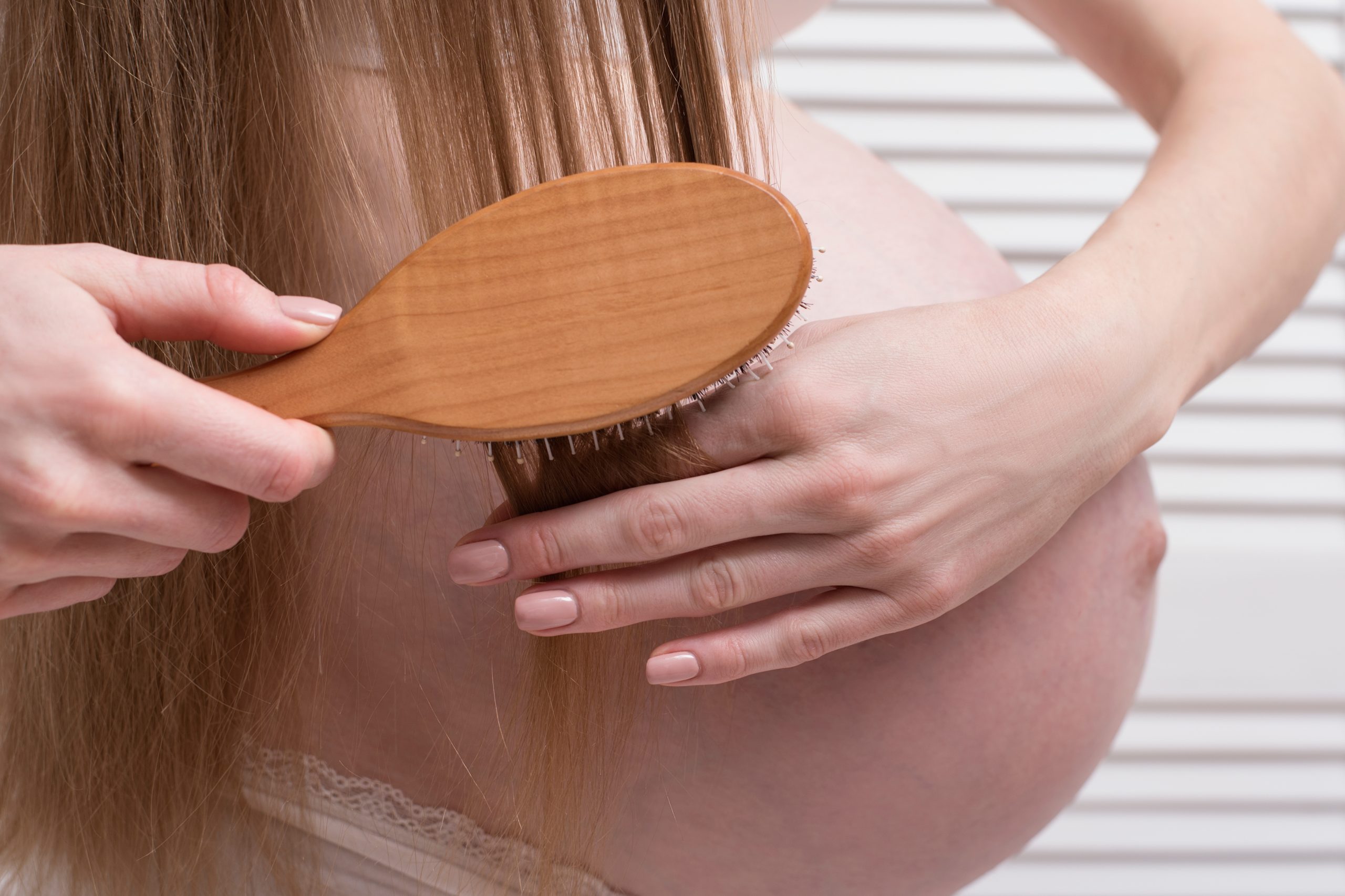 Pregnant woman combing her hair for a pregnancy-safe lice treatment article