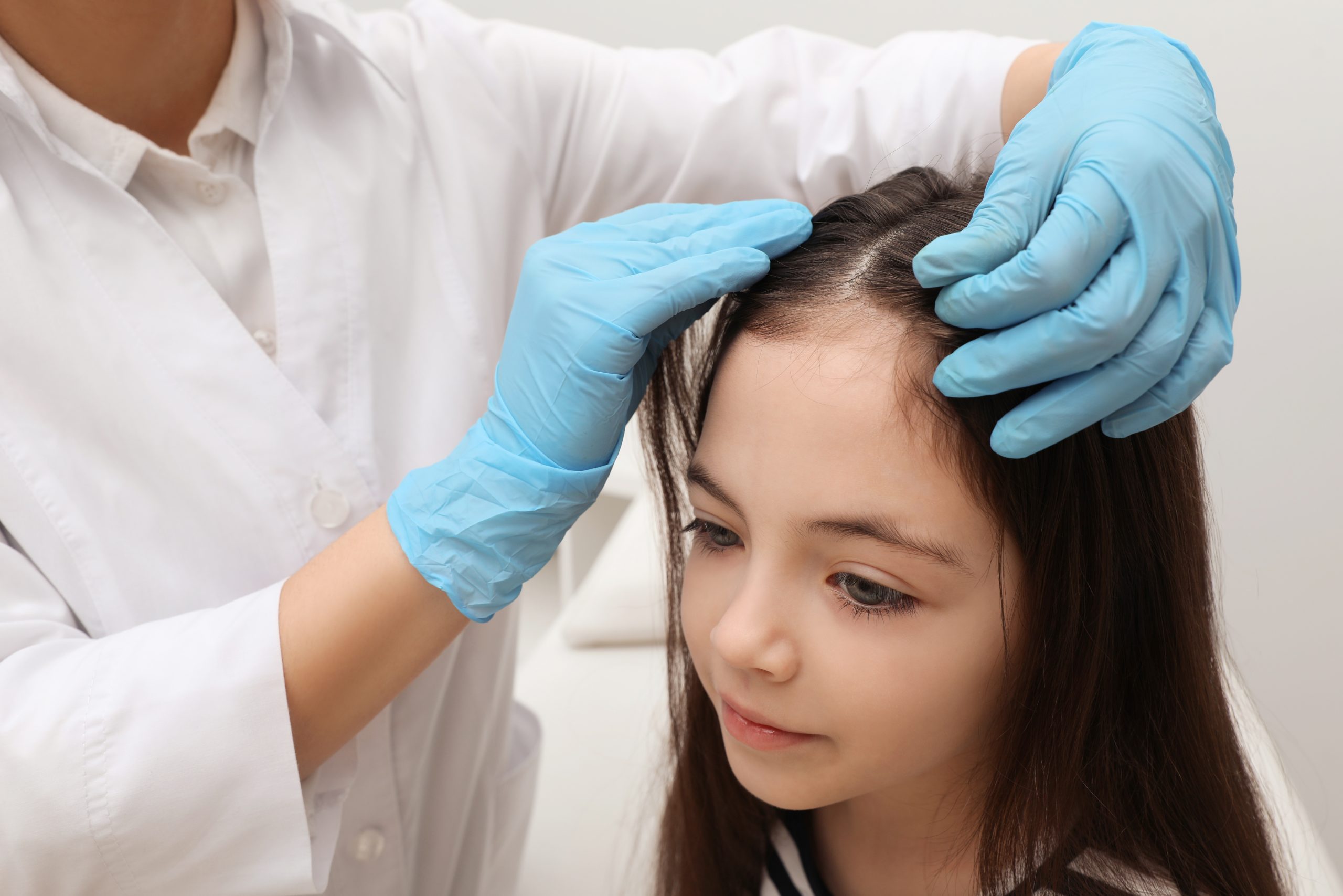 Doctor examining a child's hair during a professional lice treatment appointment