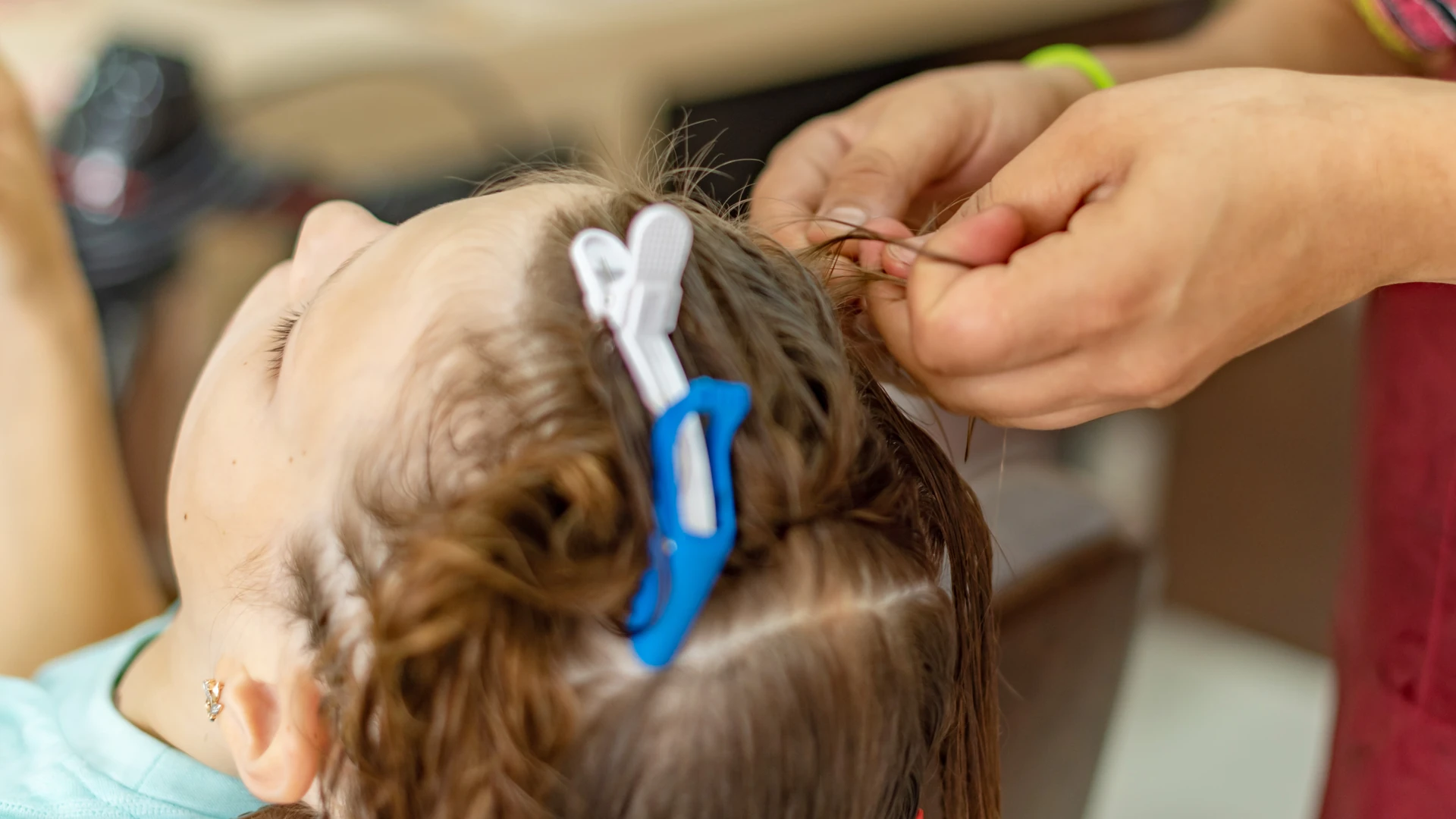 Hands separating a strand of clipped, sectioned hair.
